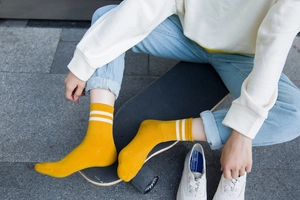 Detalle de calcetines de algodón acanalado amarillo con rayas blancas en estilo callejero