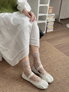 Close-up of sheer beige socks featuring blue heart patterns worn with white Mary Jane shoes