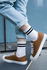 Primer plano de calcetines blancos con rayas negras usados con vaqueros y tenis marrones