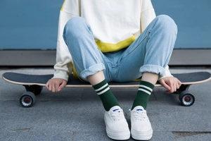 Detalle de calcetines verde oscuro con dos rayas blancas y zapatillas blancas