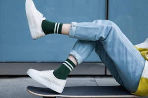 Detalle de calcetines de algodón con rayas verdes y zapatillas blancas en un monopatín