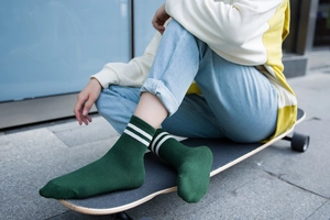 Detalle de calcetines de algodón verde oscuro con rayas blancas en un monopatín