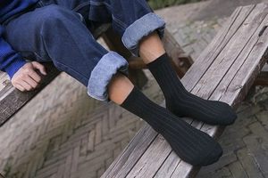 Detailed view of black vertical ribbed crew socks on a model in an outdoor setting