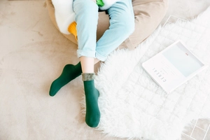 Detailaufnahme grüner Thermo-Wintersocken mit warmem Kunstfell-Aufschlag auf einem Teppich