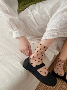 Detail of sheer glass silk socks with black heart pattern and Mary Jane flat shoes