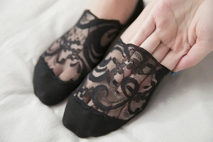 Close-up of black floral lace no-show sock showing high elasticity and sheer texture