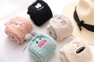 Detail of five colorful thick coral fleece socks with cute cartoon monster embroidery