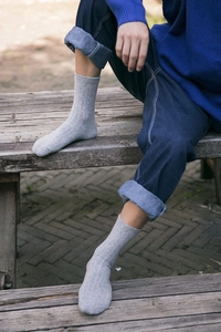 Close-up of gray ribbed wool socks for men paired with denim jeans on a wooden bench