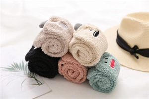 Detailed view of rolled coral fleece socks with colorful cute animal embroidery patterns