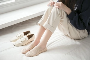 Detail of beige lace no-show socks with floral crochet pattern on model's feet