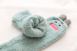 Close-up of soft green coral fleece thermal socks with cute 3D cartoon monster details