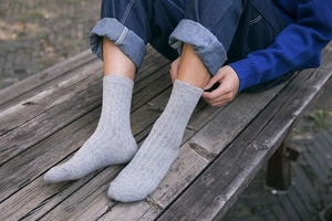 Detail of grey ribbed wool socks for men shown in an outdoor setting with jeans
