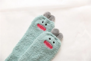 Detailed close-up of soft coral fleece monster socks with green plush and cute embroidery