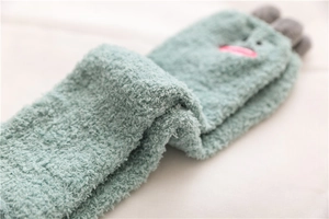 Detailed macro view of mint green coral fleece sock with cartoon face embroidery
