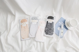 Flat lay of lace no-show socks in four colors on a white fabric background