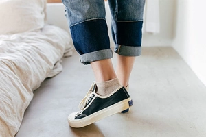 Close-up of black low-top canvas sneakers with thick white rubber soles on a model