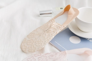 Detailed view of nude floral lace invisible socks on a soft fabric with lifestyle props