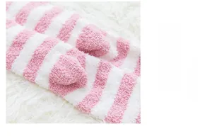 Détail de chaussettes rayées rose et blanc en polaire corail avec décorations de cœur