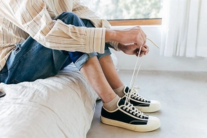 Detailed view of black low-top canvas shoes with cream toe caps and brown cotton socks