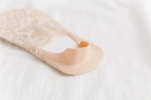Detailed macro view of beige floral lace no-show socks with non-slip silicone heel grip