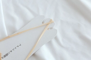Detail of beige lace trim on white cardboard packaging with fashion quality text