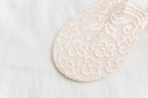 Detailed close-up of beige floral lace embroidery with fine mesh texture and petal patterns