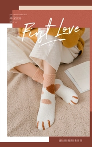 Close-up of thick coral fleece socks with cute orange cat paw embroidery and spotted pattern