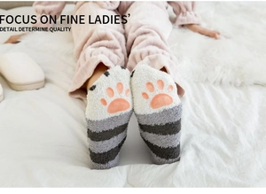 Détail des coussinets antidérapants patte de chat rose sur chaussettes rayées en polaire