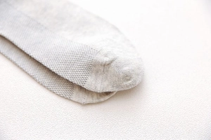 Detail of grey cotton sock showing honeycomb breathable mesh texture and seamless toe stitch