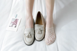 Detailed view of beige floral lace no-show socks worn with cream tasseled loafers