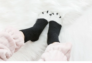 Gros plan de chaussettes de nuit patte de chat en peluche noir et blanc sur tapis