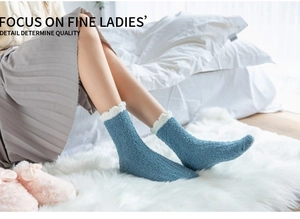 Close-up of soft light blue coral fleece socks with white fluffy faux fur trim on bed