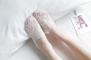 Close-up of white floral lace invisible socks showing delicate pattern and wavy edges