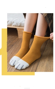 Close-up of ginger knitted socks with cute cat paw toe patterns and rolled cuffs