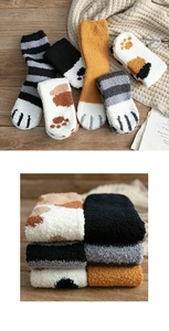 Close-up of thick coral fleece socks with cute cat paw patterns on wood background