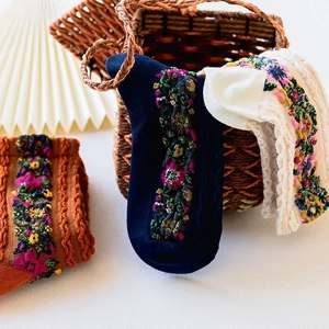 Detail of floral embroidery on knit socks in navy, cream, and caramel vintage style