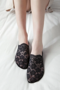 Top view of female feet wearing black floral lace invisible liner socks on white fabric