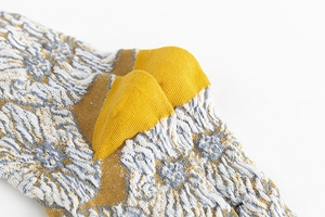 Detailed macro view of mustard yellow knit socks with floral pattern and reinforced heel