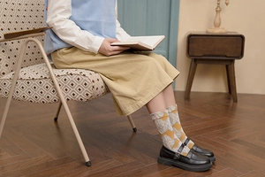 Detailed pattern of yellow floral knit socks with wavy ruffled cuffs and vintage style