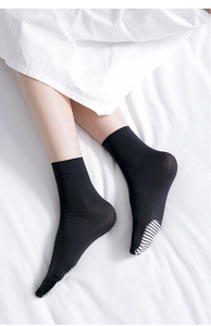 Close-up of black velvet cotton socks featuring white striped sole design on feet