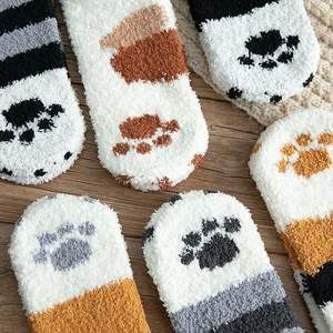 Cute cat paw coral fleece thermal socks in various colors on a warm wooden background