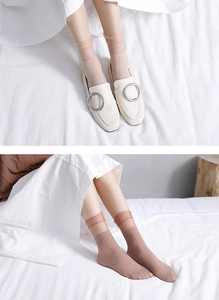 Detail of ruffled lace cuffs on sheer beige velvet socks paired with white shoes