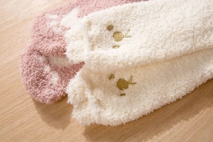 Close-up of pink star pattern and cream bunny embroidery on thick coral fleece socks