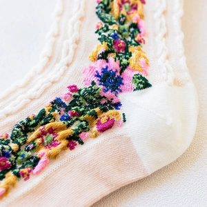 Detailed macro view of white cotton socks with colorful floral embroidery and cable knit texture
