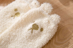 Close-up of warm cream coral fleece socks with golden bear embroidery and 3D ear details