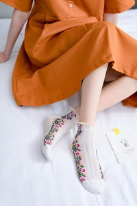 Detail of white cotton socks with colorful floral patterns and ruffled lace cuffs