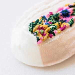 Macro shot of cotton knit socks featuring colorful floral jacquard and cable patterns