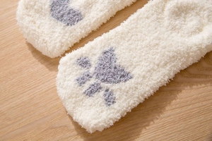 Close-up of soft coral fleece winter socks with cute grey cat paw embroidery detail