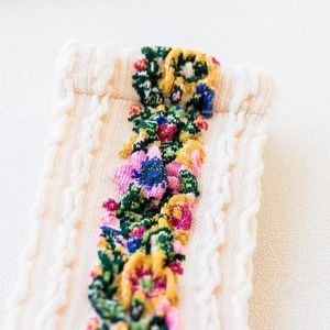 Close-up of cable knit cotton socks with vintage floral embroidery in cream white color