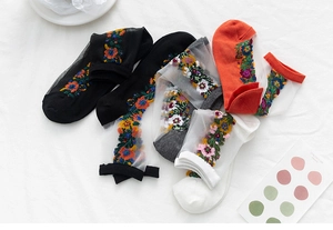 Détail de la broderie florale sur le panneau en mesh transparent de chaussettes vintage